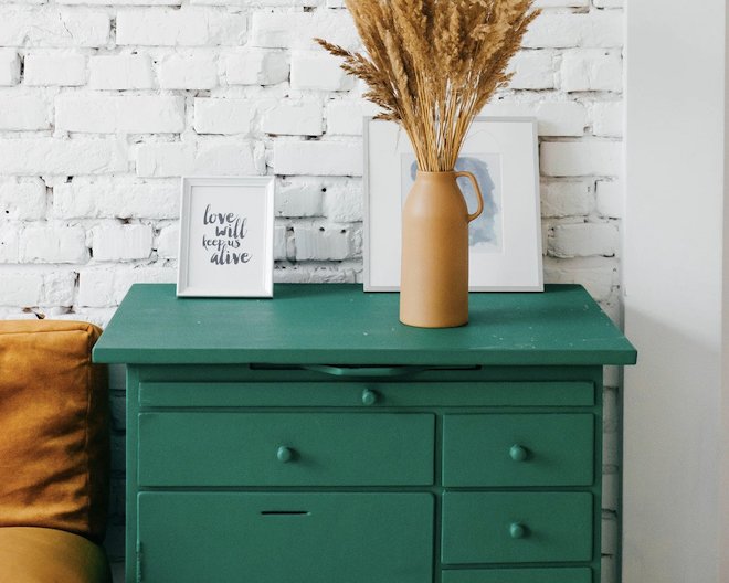 Green drawers with a vase and two things on top